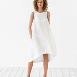 Woman wearing white sleeveless Royal Toscana linen midi dress with curved hem on white background — Magic Linen | Endless UAE