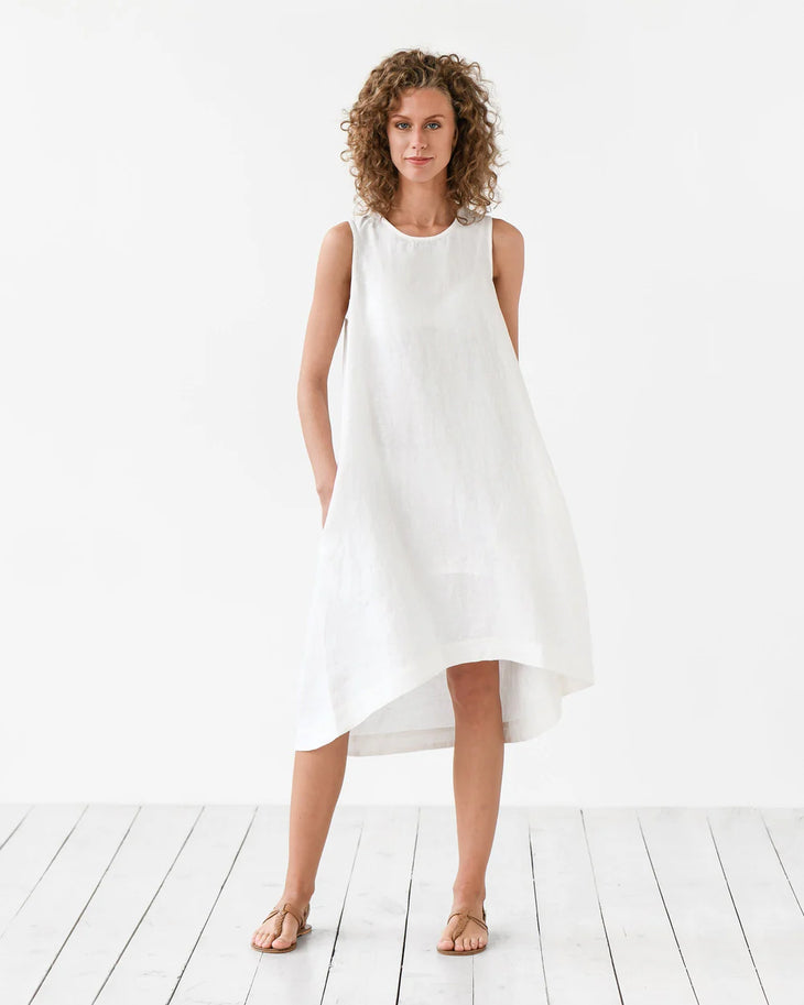 Woman wearing white sleeveless Royal Toscana linen midi dress with curved hem on white background — Magic Linen | Endless UAE
