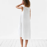 White sleeveless linen midi dress with back zipper, worn by woman with curly hair on white wooden floor — Magic Linen | Endless UAE