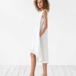 White sleeveless linen midi dress with asymmetric hem and side pockets on woman with curly hair — Magic Linen | Endless UAE