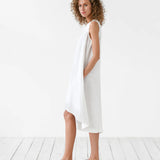 White sleeveless linen midi dress with asymmetric hem and side pockets on woman with curly hair — Magic Linen | Endless UAE