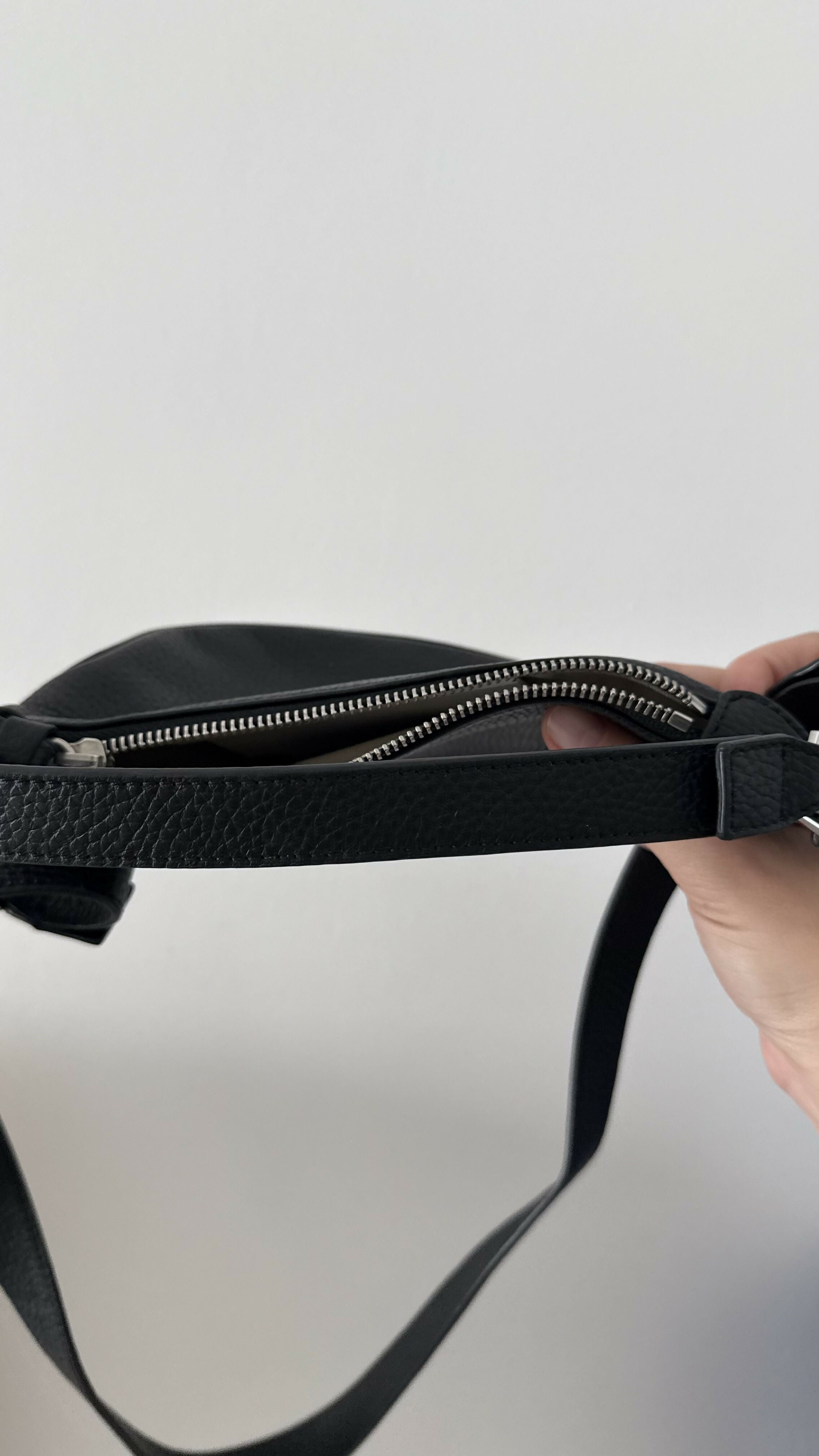 Black leather mini shoulder bag with textured finish held open to show interior — By Far | Endless UAE