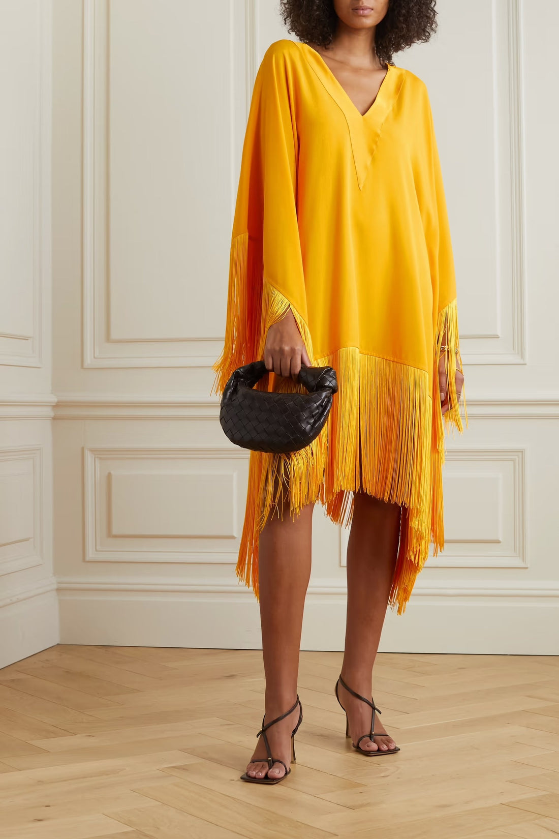 Woman wearing a yellow and orange fringed kaftan with black bag and sandals — Taller Marmo | Endless UAE