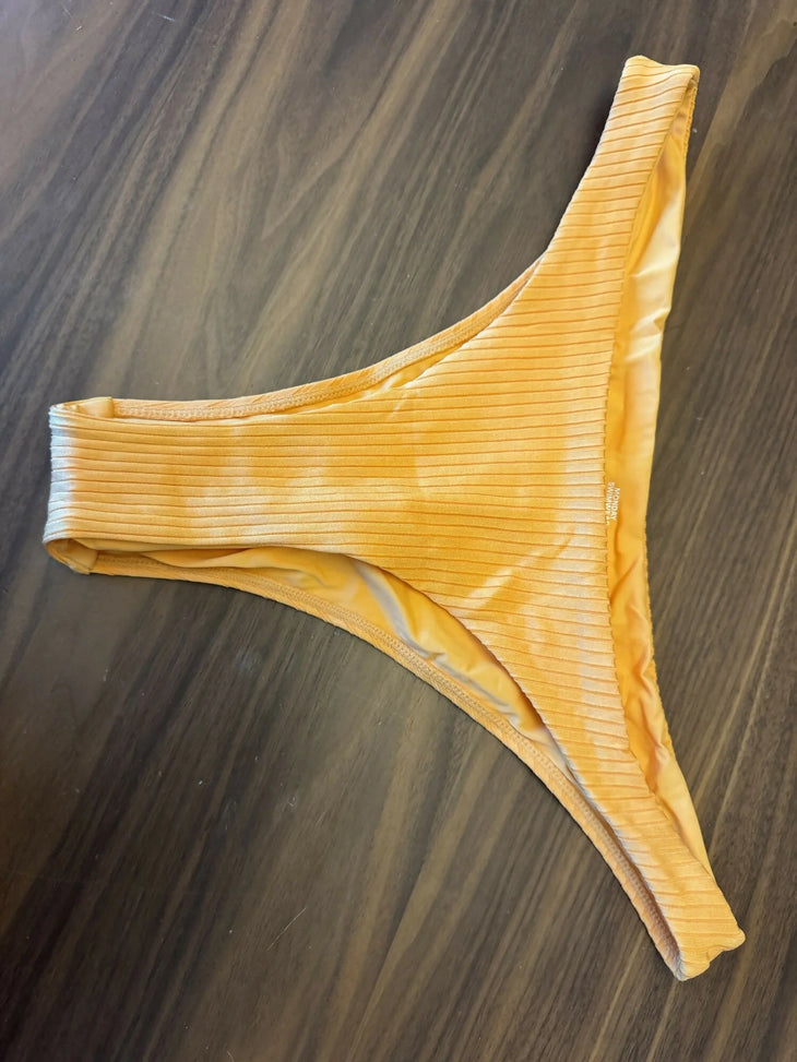 Clementine orange ribbed bikini bottom with wide straps on dark wood surface — Monday Swimwear | Endless UAE