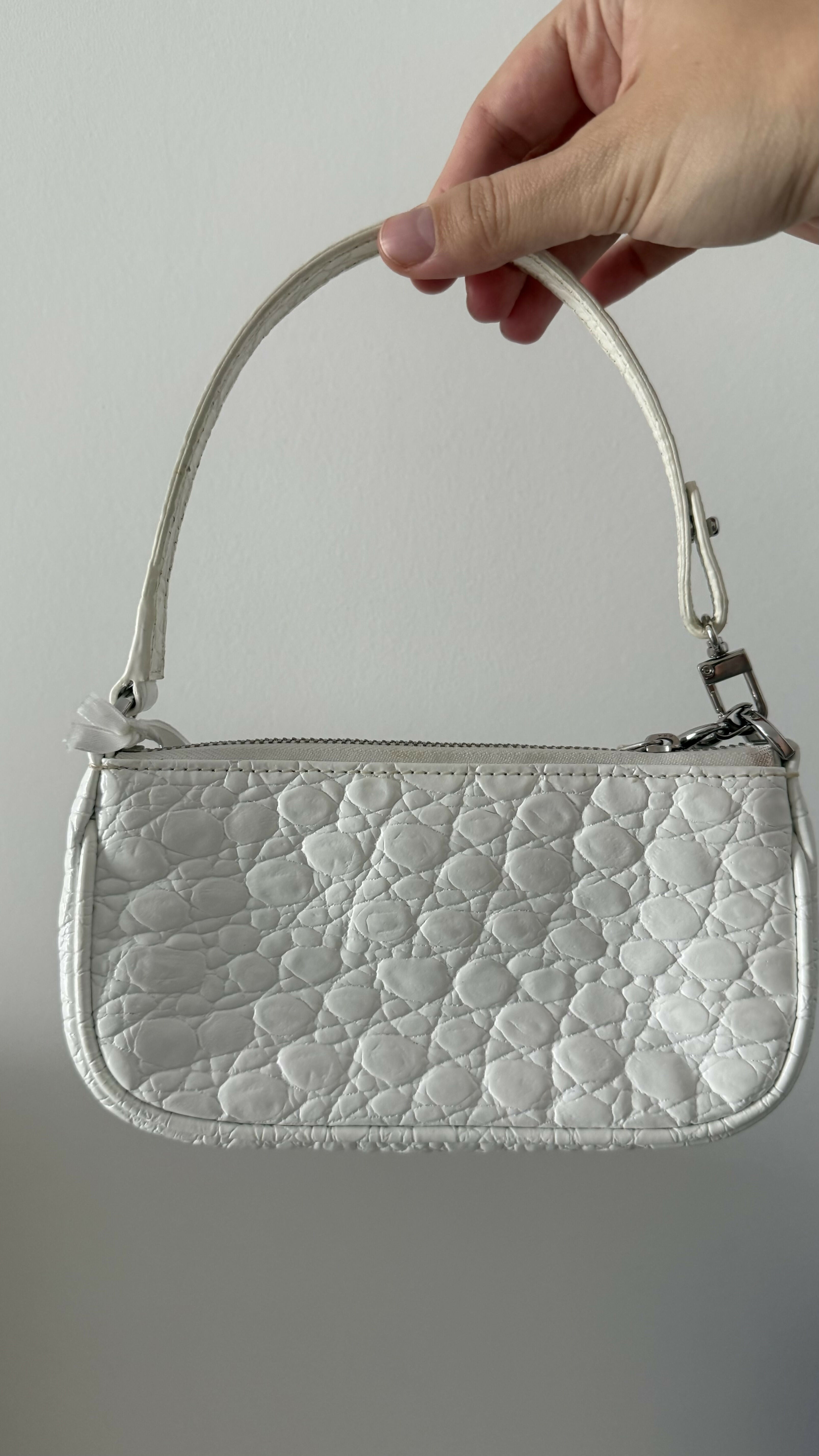 White quilted mini shoulder bag with silver hardware held up against neutral background — By Far | Endless UAE