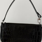 Black crocodile embossed leather shoulder bag held in hand against white background — By Far | Endless UAE