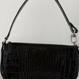 Black crocodile embossed leather shoulder bag held in hand against white background — By Far | Endless UAE