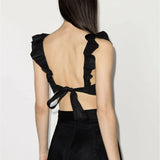 Black ruffled crop top with open back and tie detail, shown from behind — Zimmermann | Endless UAE