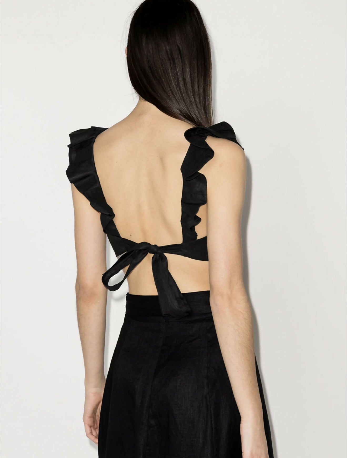 Black ruffled crop top with open back and tie detail, shown from behind — Zimmermann | Endless UAE
