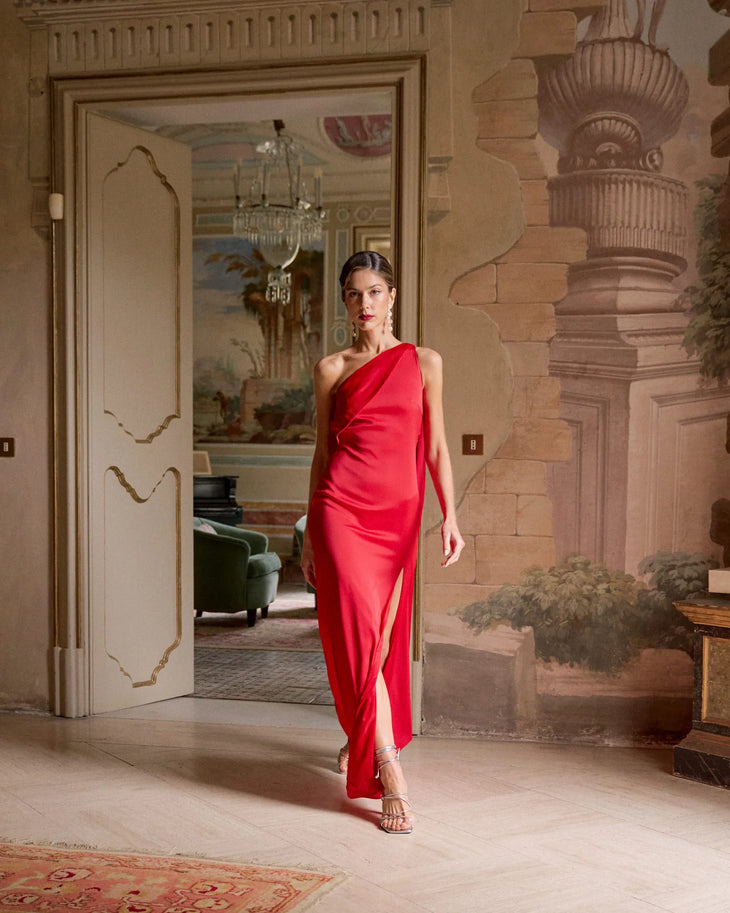 Elegant red one-shoulder satin gown with draped silhouette, worn in luxurious interior setting — Miphai | Endless UAE