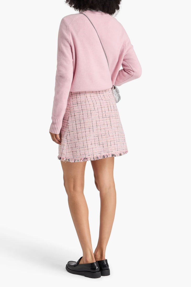 Back view of model wearing pink metallic tweed mini skirt with frayed hem paired with matching pink sweater — Maje | Endless UAE