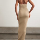Woman wearing beige ribbed jersey halterneck maxi dress with open back, rear view — Eterne | Endless UAE