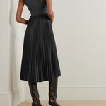 Woman wearing dark grey sleeveless midi dress with pleated skirt and knee-high leather boots — Theory | Endless UAE