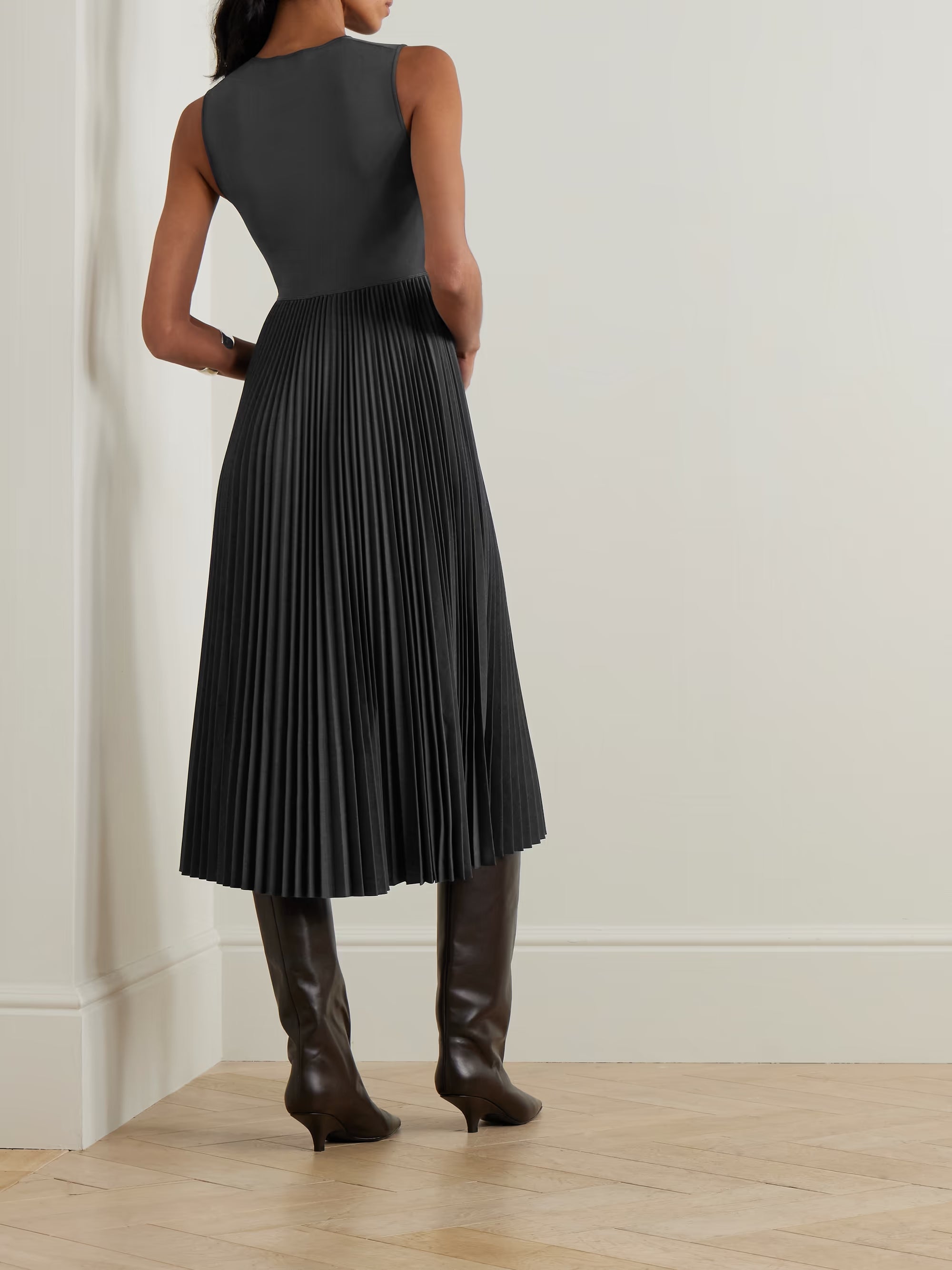 Woman wearing dark grey sleeveless midi dress with pleated skirt and knee-high leather boots — Theory | Endless UAE