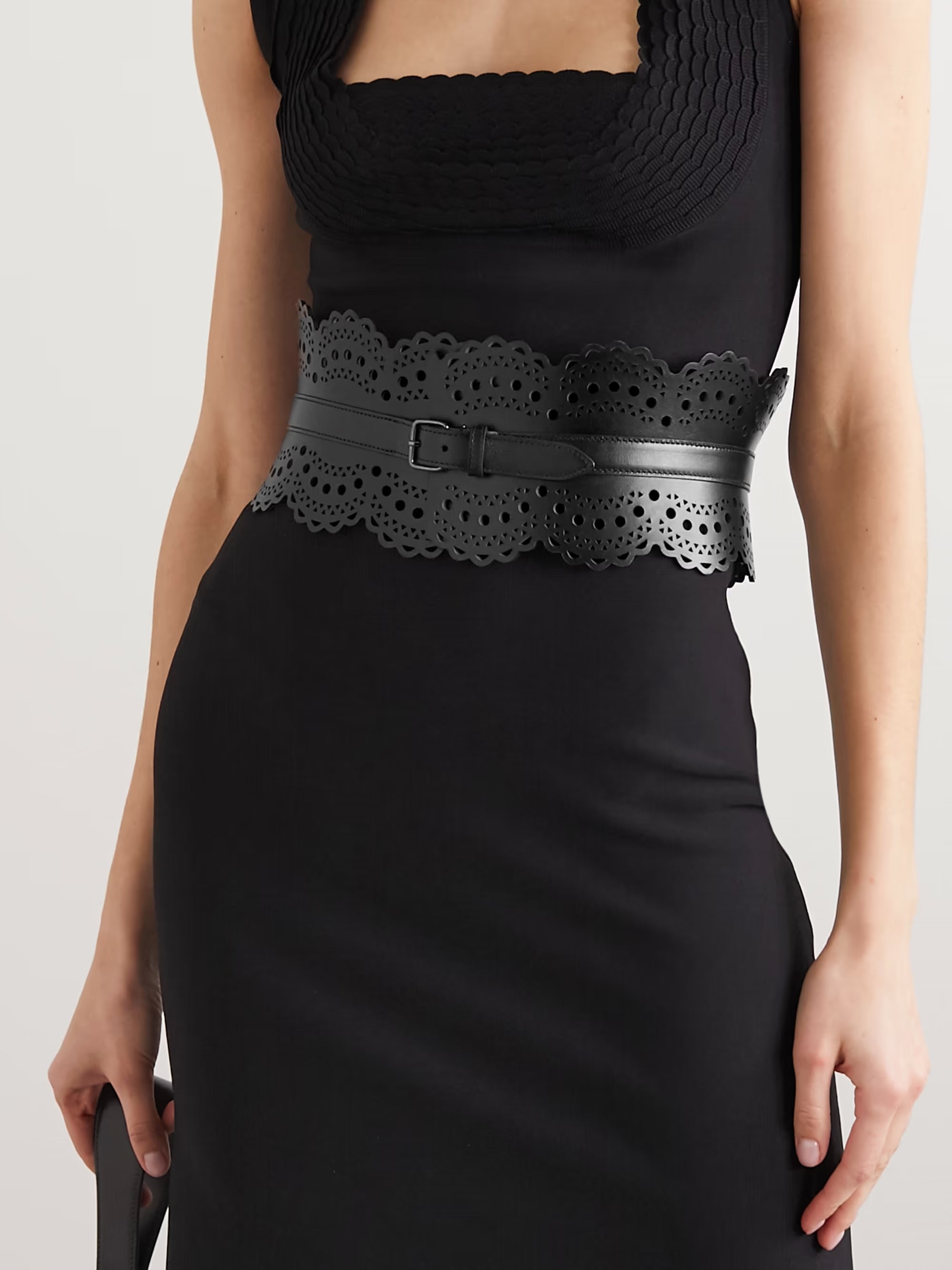 Black laser-cut leather waist belt with scalloped edges and decorative perforations, worn with black dress — Alaïa | Endless UAE
