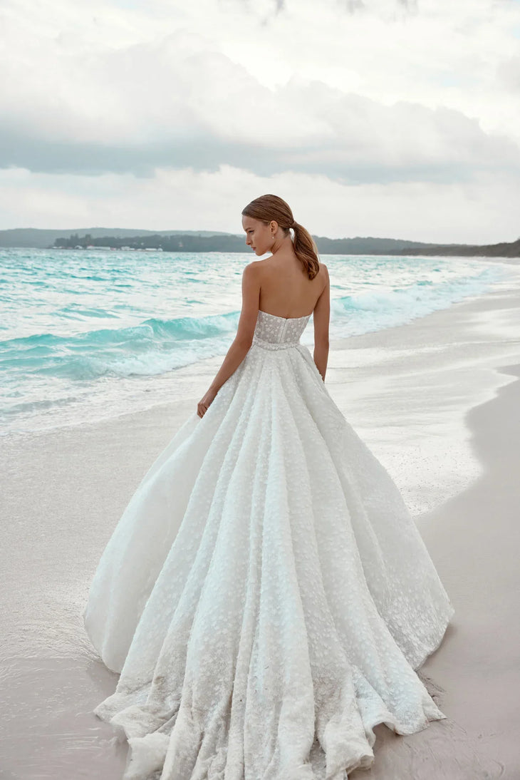 Alaia bridal gown featuring beaded bodice and flowing tulle train on beach — Wona Concept | Endless UAE