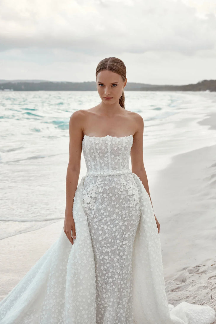 Alaia bridal gown featuring beaded bodice and flowing tulle train on beach — Wona Concept | Endless UAE