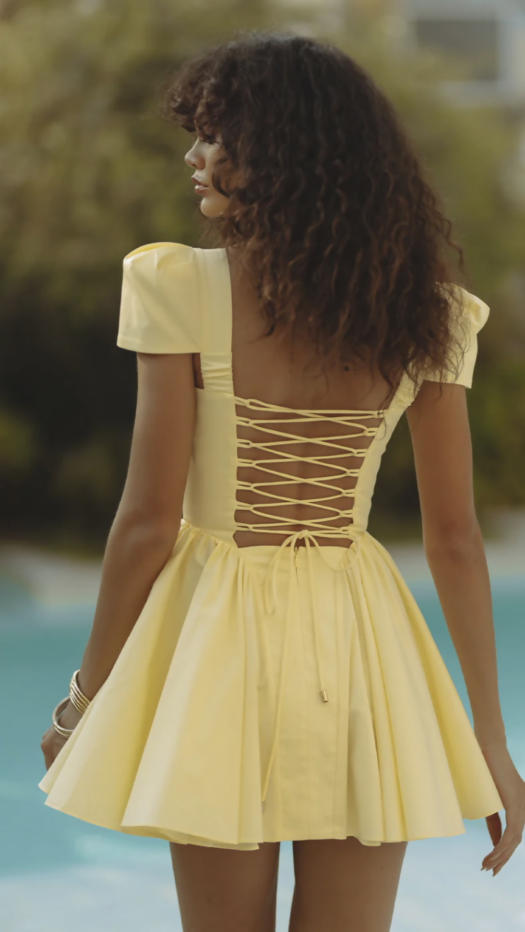 Woman wearing yellow off-shoulder mini dress with puffed sleeves by poolside — Endless | Endless UAE