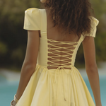 Woman wearing yellow off-shoulder mini dress with puffed sleeves by poolside — Endless | Endless UAE
