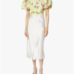 Woman wearing yellow floral puff-sleeve top with white midi skirt and blue sandals — Rotate Birger Christensen | Endless UAE