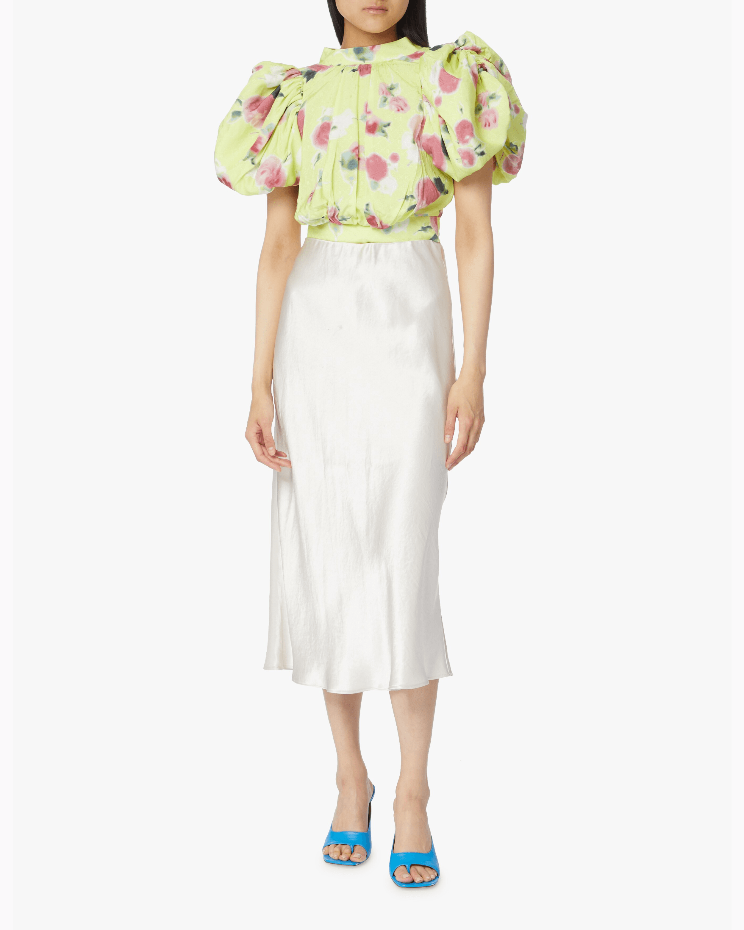 Woman wearing yellow floral puff-sleeve top with white midi skirt and blue sandals — Rotate Birger Christensen | Endless UAE