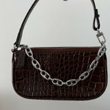 Dark brown croc-embossed mini shoulder bag with chain detail held in hand — By Far | Endless UAE