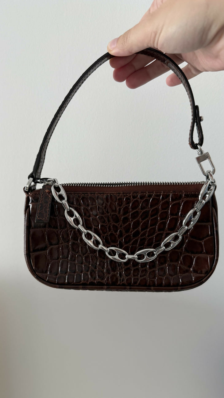 Dark brown croc-embossed mini shoulder bag with chain detail held in hand — By Far | Endless UAE