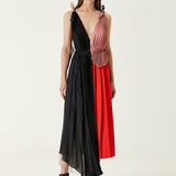 Woman wearing pleated asymmetric maxi dress in black, blush pink and red with black ankle strap heels — Victoria Beckham | Endless UAE