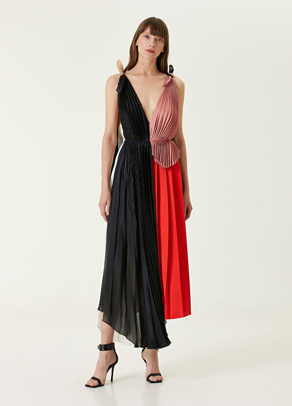 Woman wearing pleated asymmetric maxi dress in black, blush pink and red with black ankle strap heels — Victoria Beckham | Endless UAE