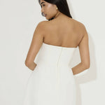 Woman wearing white strapless mini dress with back zipper closure, viewed from behind — Odd Muse | Endless UAE
