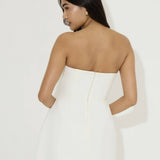 Woman wearing white strapless mini dress with back zipper closure, viewed from behind — Odd Muse | Endless UAE
